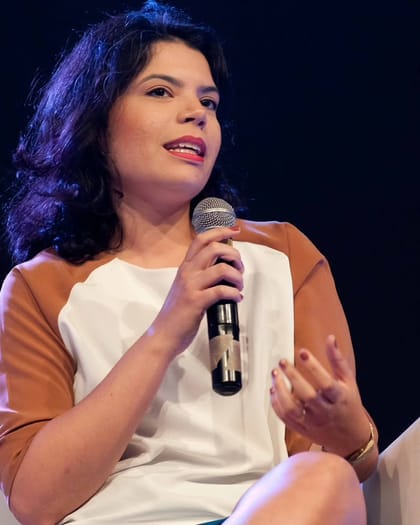 Raisa Arruda falando ao microfone durante uma palestra.